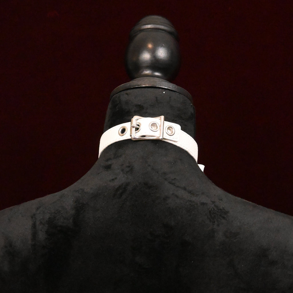 White collar with silver buckle on a black mannequin on dark background