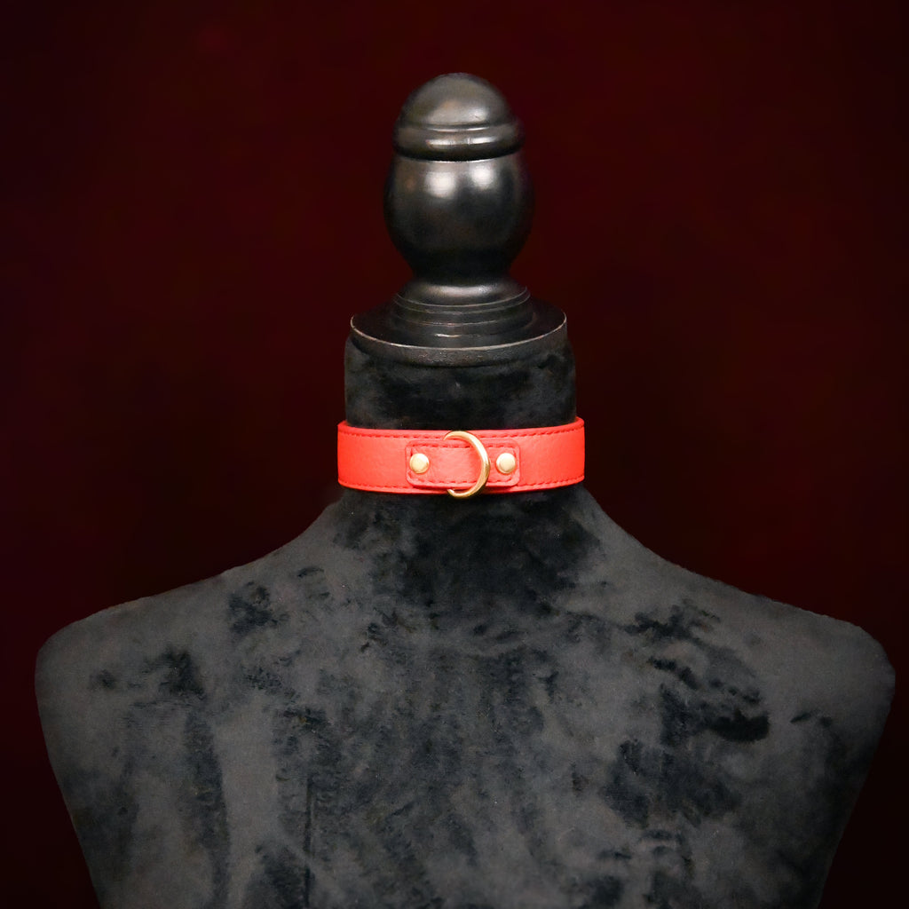 Red leather collar on a black mannequin against a dark background