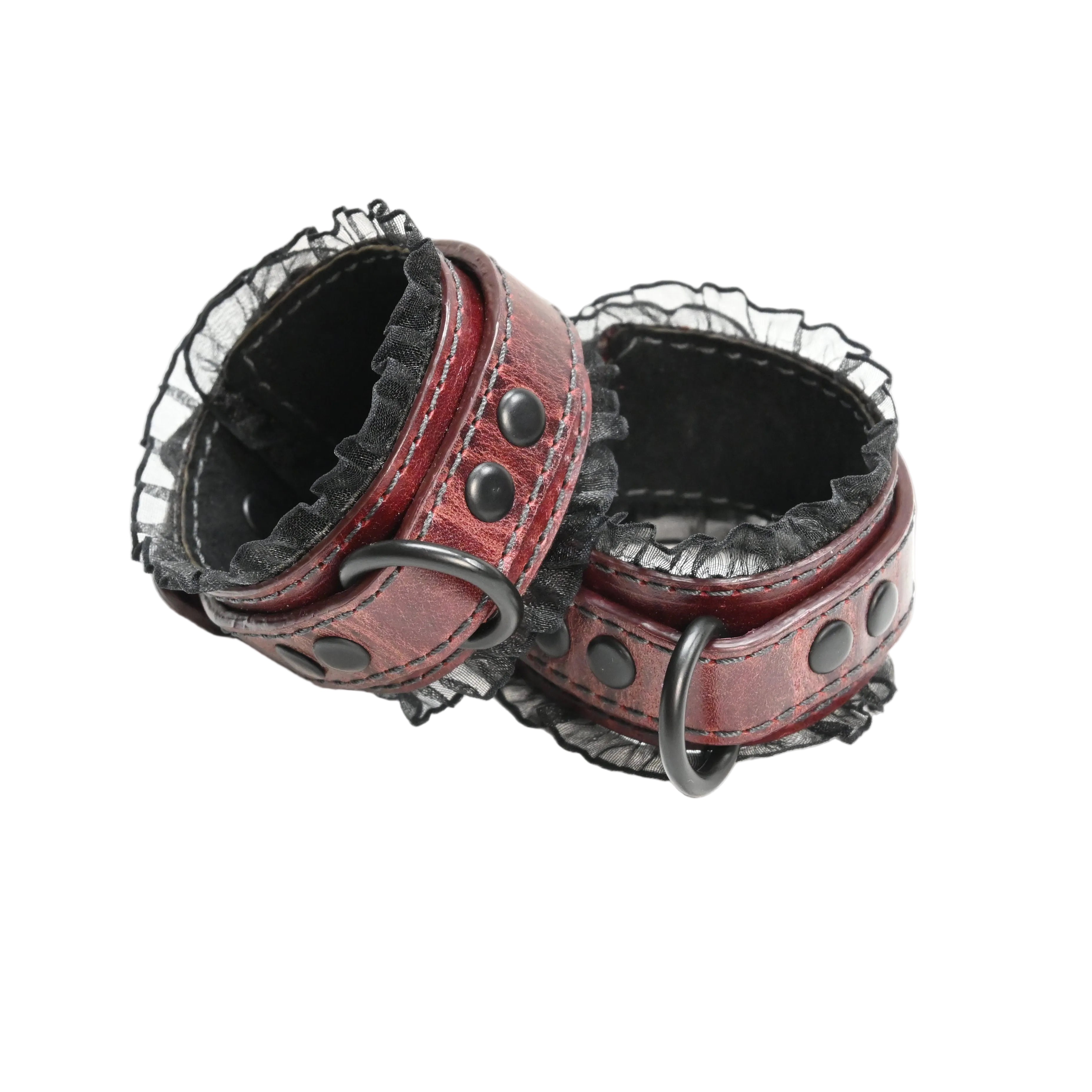 A pair of red leather wrist cuffs with black lace trim, black suede lining, and black metal rings and rivets, photographed on a plain white background.