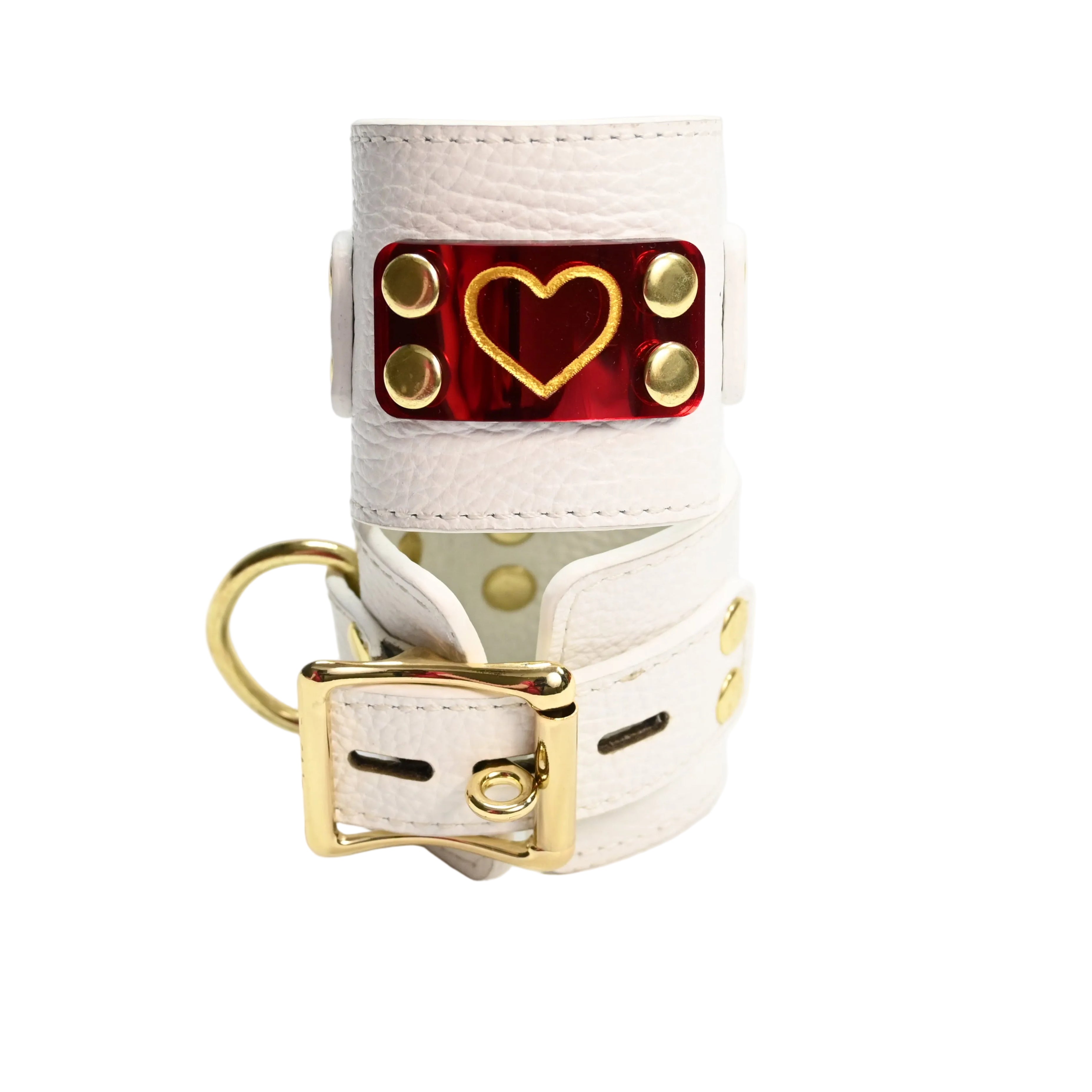 Two stacked white leather cuffs with gold hearts on red heart acrylic plates, gold rivets, and gold D rings and gold buckle, photographed on a clean white background.