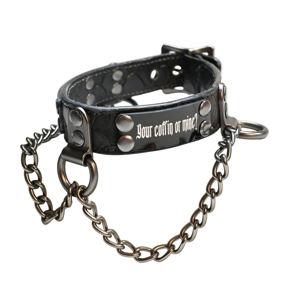 A black leather collar with silver studs, a black metal chain, and the text 'your coffin or mine?' printed in white on the front, resting on a white background.