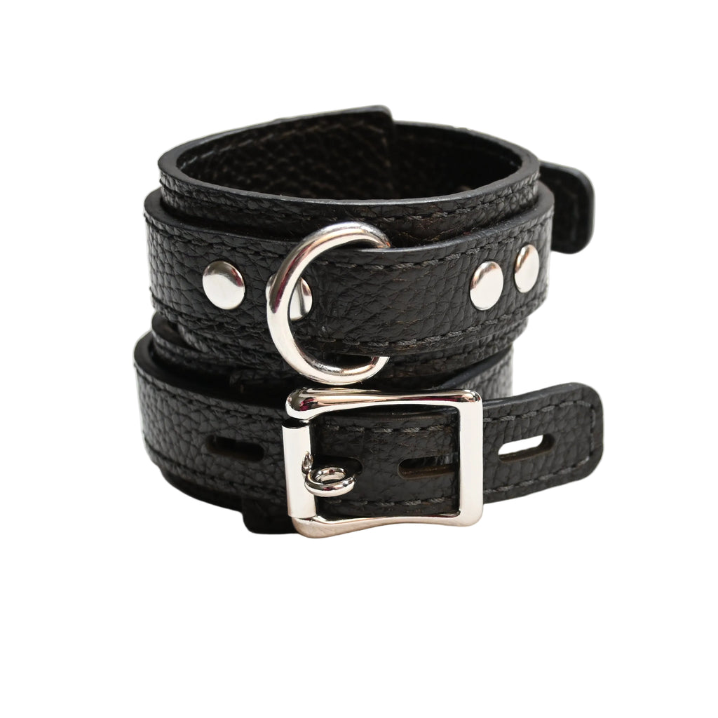 Two black leather cuffs with silver metal D rings , buckles, and rivets, displayed on a clean white surface.