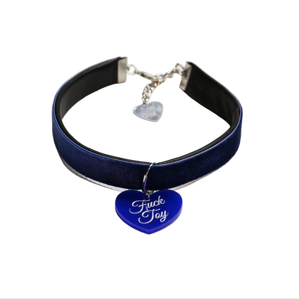 A dark blue velvet choker collar with a silver-tone metal clasp and a blue heart-shaped charm engraved with the words 'Fuck Toy' in white script, displayed on a white background.
